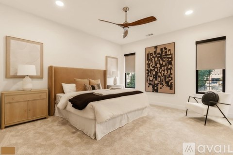 A bedroom with a large bed, a ceiling fan, and a painting on the wall.