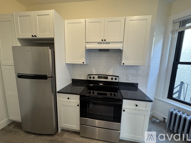 A kitchen with white cabinets and a black countertop.