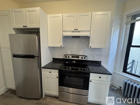 A kitchen with white cabinets and a black countertop.