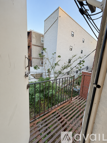 A balcony with a metal railing and a building in the background.
