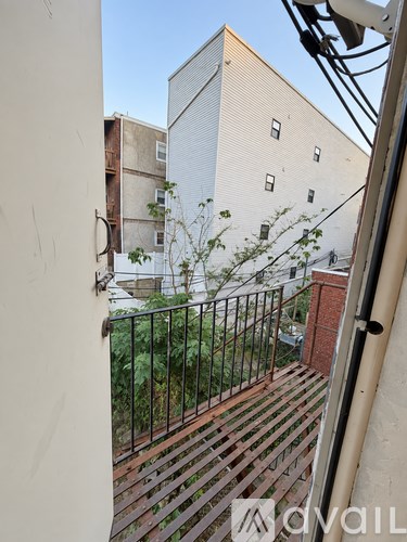 A balcony with a metal railing and a building in the background.