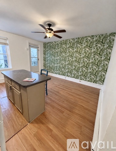 A kitchen with a ceiling fan and wooden floors.