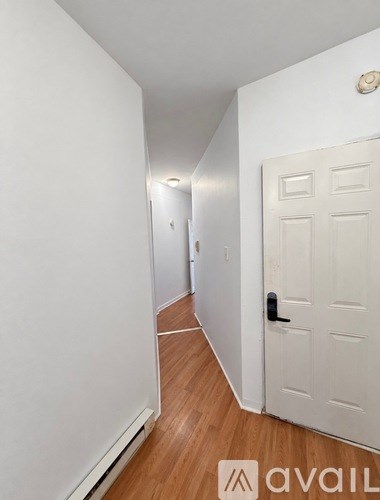 A hallway with a white door and wooden floors.