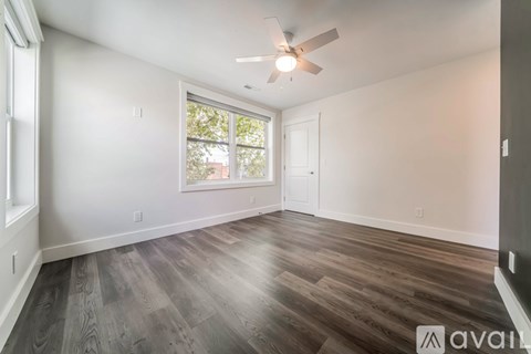 A room with a ceiling fan and a window with a view of trees.