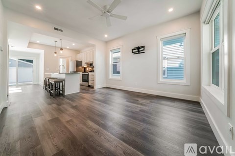 A spacious room with wooden flooring and a ceiling fan.