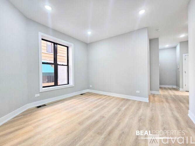 A spacious room with wooden flooring and a window.