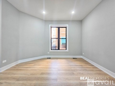 A spacious room with wooden flooring and a large window.