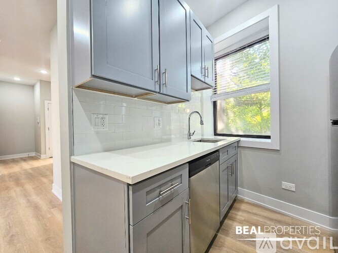 A kitchen with a stainless steel dishwasher and a white countertop.