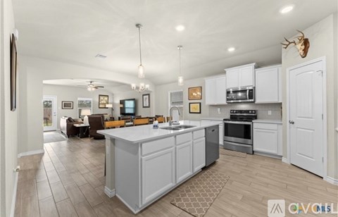A kitchen with white cabinets and a wooden island.