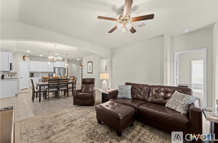 A living room with a brown leather couch and a dining table.
