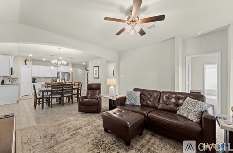 A living room with a brown leather couch and a dining table.