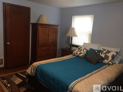 A bedroom with a bed, dresser, and lamp.