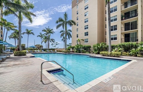 A swimming pool surrounded by palm trees and a building in the background.