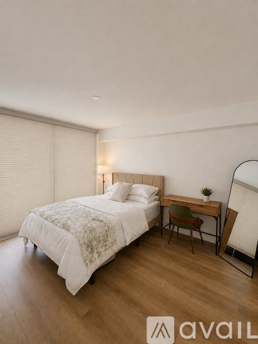 A bedroom with a bed, desk, and chair.