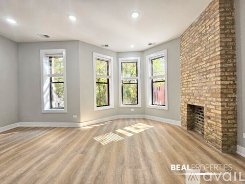 A room with a brick fireplace and wooden floors.