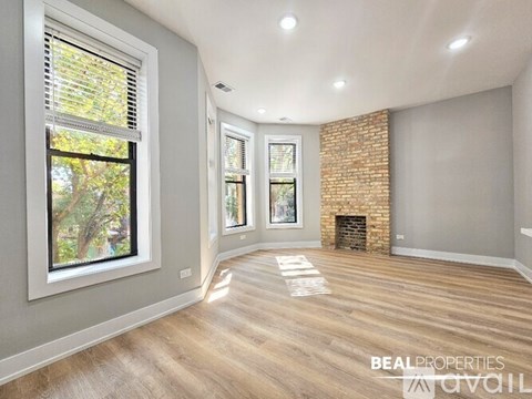 A spacious room with a fireplace and a brick wall.