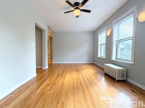 A room with wooden floors and a ceiling fan.