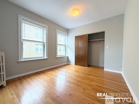 A room with wooden floors and a door leading to a bathroom.