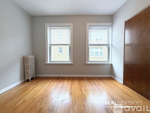A room with wooden floors and two windows.