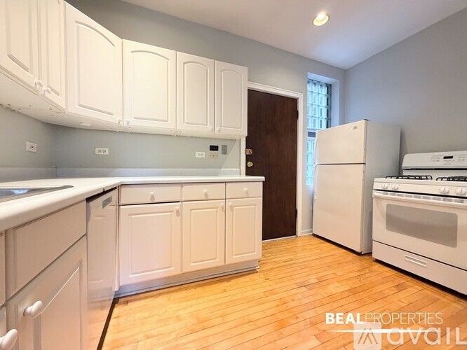 A kitchen with white cabinets and a wooden floor.