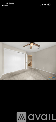 A room with a ceiling fan and a door leading to another room.