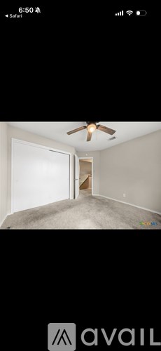 A room with a ceiling fan and a door leading to another room.