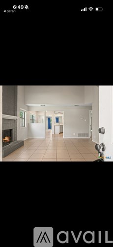 A modern living room with a fireplace and a kitchen area in the background.