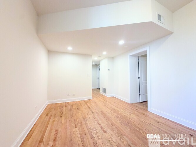 A spacious room with wooden flooring and white walls.