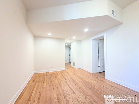 A spacious room with wooden flooring and white walls.