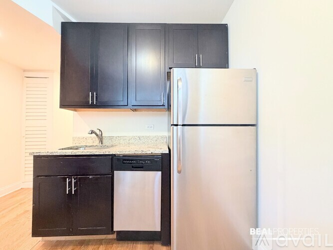 A kitchen with black cabinets and a stainless steel refrigerator.