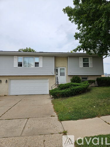 A house with a grey siding and a white garage door is for sale.