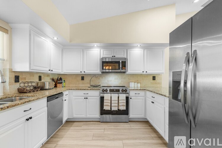 A modern kitchen with white cabinets and stainless steel appliances.