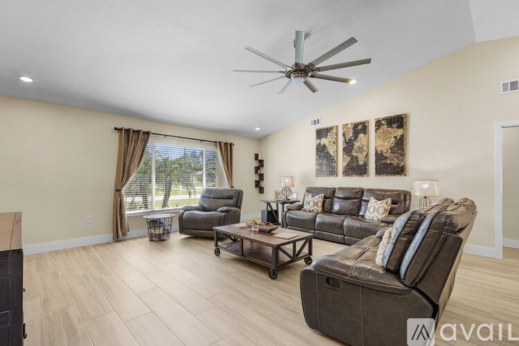 A living room with a brown leather couch and a ceiling fan.