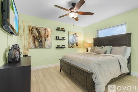 A bedroom with a bed, a ceiling fan, and a painting of an elephant on the wall.