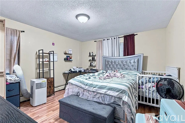 A bedroom with a bed, nightstand, and a fan.