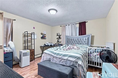 A bedroom with a bed, nightstand, and a fan.