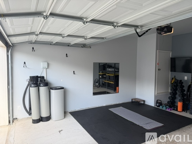 A gym with a black mat and a mirror on the wall.
