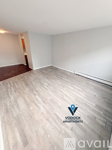 A spacious empty room with Vodock Apartments logo on the floor.