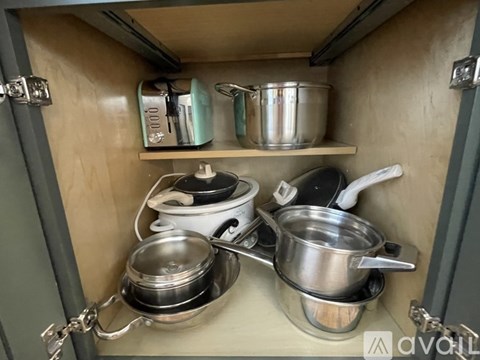 A kitchen cabinet with pots and pans.