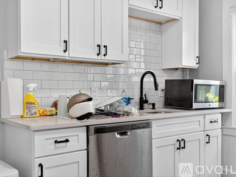 A kitchen with white cabinets and a black dishwasher.