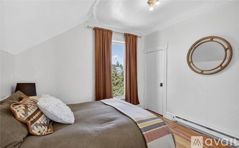 A bedroom with a bed, pillows, and a mirror on the wall.