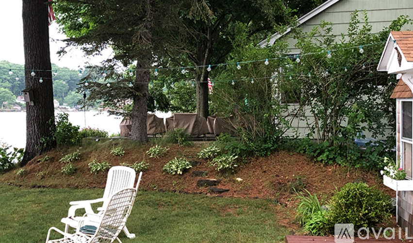 A white chair is on a lawn in front of a house.