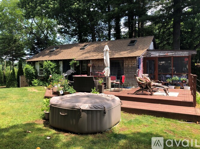 A hot tub is in the foreground of a backyard with a house and deck in the background.