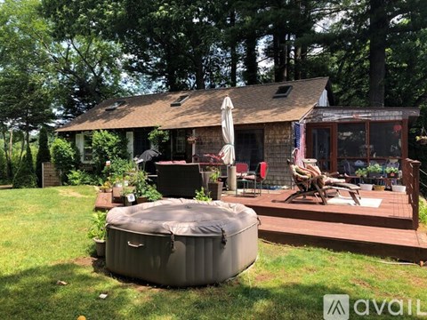 A hot tub is in the foreground of a backyard with a house and deck in the background.