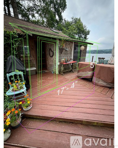 A wooden deck with a house and a chair with flowers on it.