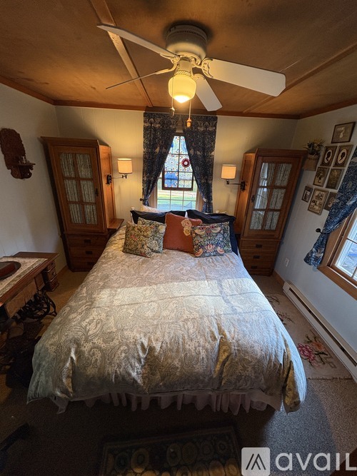 A bedroom with a bed, a ceiling fan, and a window with curtains.