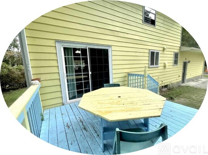 A yellow house with a blue deck and a table.