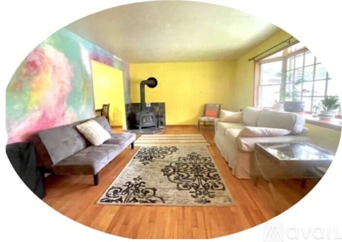 A living room with a grey couch and a black and white rug.