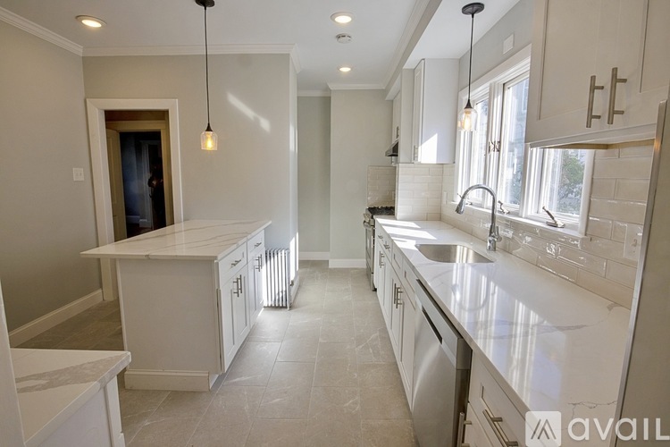 A modern kitchen with white cabinets and a marble countertop.