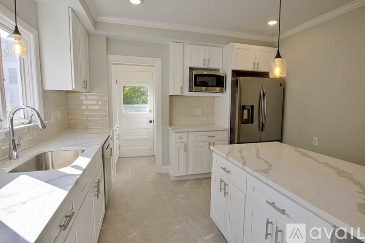 A kitchen with white cabinets and a marble countertop.